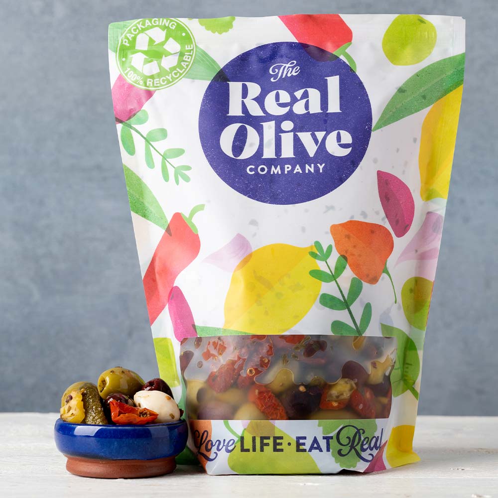 A resealable 1kg foodservice pouch of antipasti olives with a small bowl of antipasti next to it.