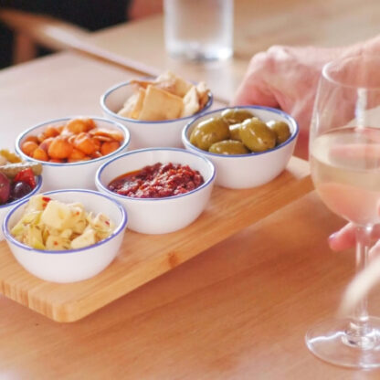 A complete hardware meze board being served and placed onto a table with drinks around it.