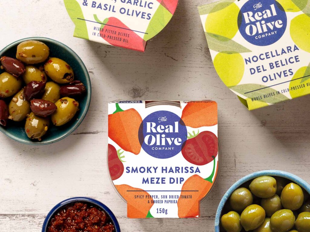 A selection of The Real Olive Company retail pots of olives and Harissa meze dip in stand out packaging and bowls filled with the products.